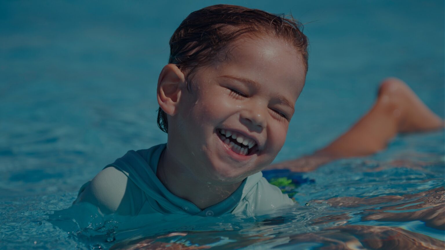 Boy swimming in pool having a good time.